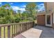Back porch with wood railing and brick siding, looking out to a yard full of trees at 1213 Walnut St, Cary, NC 27511