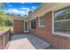 Back porch featuring brick wall, natural light, and view of lush trees at 1213 Walnut St, Cary, NC 27511