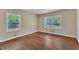 Empty bedroom featuring hardwood floors, neutral paint, and two windows at 1213 Walnut St, Cary, NC 27511