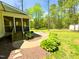 Landscaped backyard with brick patio, mulch, and stairs up to the porch at 122 American Rd, Timberlake, NC 27583