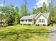 Single-story home featuring a well-manicured lawn, mature trees and a paved driveway at 122 American Rd, Timberlake, NC 27583