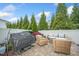 Cozy outdoor patio with stone flooring, a grill, and wicker furniture surrounded by tall trees and a white fence at 140 Torrey Heights Ln, Durham, NC 27703