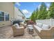 Cozy outdoor patio with stone flooring, a grill, and wicker furniture surrounded by tall trees and a white fence at 140 Torrey Heights Ln, Durham, NC 27703