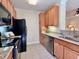 Efficient kitchen with black appliances, granite counters, wood cabinets, and tile floors at 1521 Providence Glen Dr # 1521, Chapel Hill, NC 27514