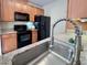 Modern kitchen with stainless steel sink, black appliances, granite counters, and wood cabinets at 1521 Providence Glen Dr # 1521, Chapel Hill, NC 27514