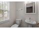 Modern half bathroom featuring a pedestal sink, mirror and a window with natural light at 1808 Elkpark Dr, Raleigh, NC 27610