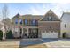 Charming two-story brick home featuring a two-car garage, covered entry, and manicured landscaping at 1911 Firenza Dr, Apex, NC 27502