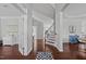 Open foyer with hardwood flooring, staircase with dark wood railing, and views into adjacent rooms at 1911 Firenza Dr, Apex, NC 27502
