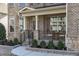 Inviting front porch with seating, decorative columns, brick accents, and landscaped garden beds at 1911 Firenza Dr, Apex, NC 27502