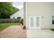 A brick patio connects to double doors surrounded by a grass lawn and trees at 228 Adefield Ln, Holly Springs, NC 27540