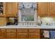Close-up of a kitchen sink area with a garden window, decorative valance, and modern faucet at 2456 Nealwood Ave, Graham, NC 27253
