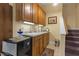 Cozy kitchenette features wooden cabinets, countertop, sink, and mini fridge next to stairway at 2456 Nealwood Ave, Graham, NC 27253