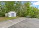 White shed with gray doors and concrete driveway on a large, tree-filled lot at 2456 Nealwood Ave, Graham, NC 27253