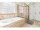 Bright bathroom featuring a soaking tub, tiled walls, glass shower and light from a glass block window at 249 Mill Creek Dr, Clayton, NC 27527