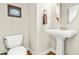 Small powder room with wood floors features a pedestal sink, toilet, and framed picture at 249 Mill Creek Dr, Clayton, NC 27527
