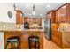 Well-lit kitchen boasts wooden cabinets, stainless steel refrigerator, breakfast bar, and hardwood floors at 249 Mill Creek Dr, Clayton, NC 27527