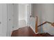 Hallway with hardwood floors leading to carpeted room, featuring a wooden railing at 256 William Drummond Way, Raleigh, NC 27604