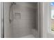 Modern walk-in shower with gray tiling, built-in niche, and a glass door at 256 William Drummond Way, Raleigh, NC 27604