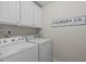 Functional laundry room with white appliances, storage cabinets, and a decorative laundry sign at 2812 Lemnos Dr, Apex, NC 27502