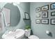 Charming powder room features a pedestal sink, round mirror, and gallery wall at 2812 Lemnos Dr, Apex, NC 27502