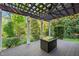 A covered patio has stylish furniture, lighting, and views of the lush greenery at 314 Hogan Woods Cir, Chapel Hill, NC 27516