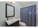 Bathroom with vanity, dark wood cabinet, framed mirror, and tiled shower with a blue patterned curtain at 314 Hogan Woods Cir, Chapel Hill, NC 27516