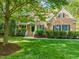 Charming brick home with a well-manicured lawn, lush greenery, and a welcoming front porch at 314 Hogan Woods Cir, Chapel Hill, NC 27516