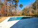 Backyard inground swimming pool surrounded by tiled patio and framed by a black fence and trees at 3416 Edgemont Dr, Raleigh, NC 27612
