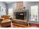 Close up of stone fireplace with white mantle and hearth, near a window and leather chair at 3428 Hardwood Dr, Apex, NC 27539
