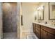 Bathroom featuring a walk-in shower with tiled walls and a double vanity with dark wood cabinets at 37 Blue Spruce Cir, Clayton, NC 27527