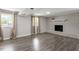 Open basement featuring gray hardwood floors, a cozy fireplace, and abundant natural light from two windows at 3713 Arrowwood Dr, Raleigh, NC 27604