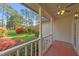 Covered porch featuring red decking, a ceiling fan, manicured landscaping, and picturesque wooded views at 50 Gill Ln, Fuquay Varina, NC 27526