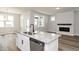 Open-concept kitchen with island, stainless steel sink, and a view of the fireplace and living area at 528 Folk Song Way, Wendell, NC 27591