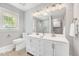 Updated bathroom with double sinks, elegant lighting, and neutral tile walls and floor at 612 E Academy St, Fuquay Varina, NC 27526