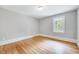 Bright bedroom featuring neutral walls, hardwood floors, and natural light from a window at 612 E Academy St, Fuquay Varina, NC 27526