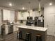 Bright kitchen boasts white cabinets, quartz countertops, stainless steel appliances, and a center island at 6332 Andante Ave, Raleigh, NC 27616