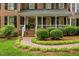 Welcoming front porch with brick walkway, lush bushes, and seasonal flowerpots at 7709 Oakmont Pl, Raleigh, NC 27615