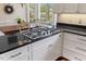 Kitchen island with black granite countertops and built-in gas cooktop at 7709 Oakmont Pl, Raleigh, NC 27615
