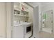 Bright laundry room with modern washer, dryer, and built-in storage shelves at 7709 Oakmont Pl, Raleigh, NC 27615