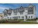 Modern townhome exterior featuring a gray and white color scheme, multiple windows and a well-manicured lawn at 801 Hyperion Aly, Wake Forest, NC 27587