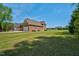 Wide view of an attractive brick house, green lawn, and large trees on a sunny day at 88 Eltham, Rocky Mount, NC 27804