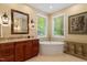 Spa-like bathroom with a freestanding tub, wooden cabinets, and bright lighting at 919 Woodham, Pittsboro, NC 27312
