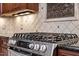 Stainless steel gas range sits beneath granite countertops and a diamond pattern tile backsplash at 919 Woodham, Pittsboro, NC 27312