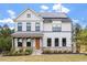 Beautiful two-story home with white brick, stone accents, dark trim, a front porch, and solar panels at 956 The Parks Dr, Pittsboro, NC 27312