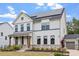Stylish two-story home featuring white brick, dark trim, solar panels, and a charming covered porch at 956 The Parks Dr, Pittsboro, NC 27312