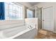 Bright bathroom featuring a soaking tub beneath a decorative window and a glass-enclosed shower at 1018 Sweet Cream Ct, Durham, NC 27703