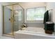 Bright bathroom features a tub with tiled surround and a glass-enclosed shower with gold trim at 102 Windrock Lane, Cary, NC 27518