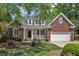 Charming brick home featuring a welcoming front porch, attached garage, and lush landscaping at 103 Temple Gate Dr, Cary, NC 27518