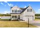 Charming two-story white farmhouse featuring black shutters, large front yard and a two-car garage at 105 Blooms Way, Kenly, NC 27542