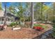 View of the backyard featuring mature trees, flower beds, a white arbor, and a white picket fence at 1100 Queensbury Cir, Durham, NC 27713
